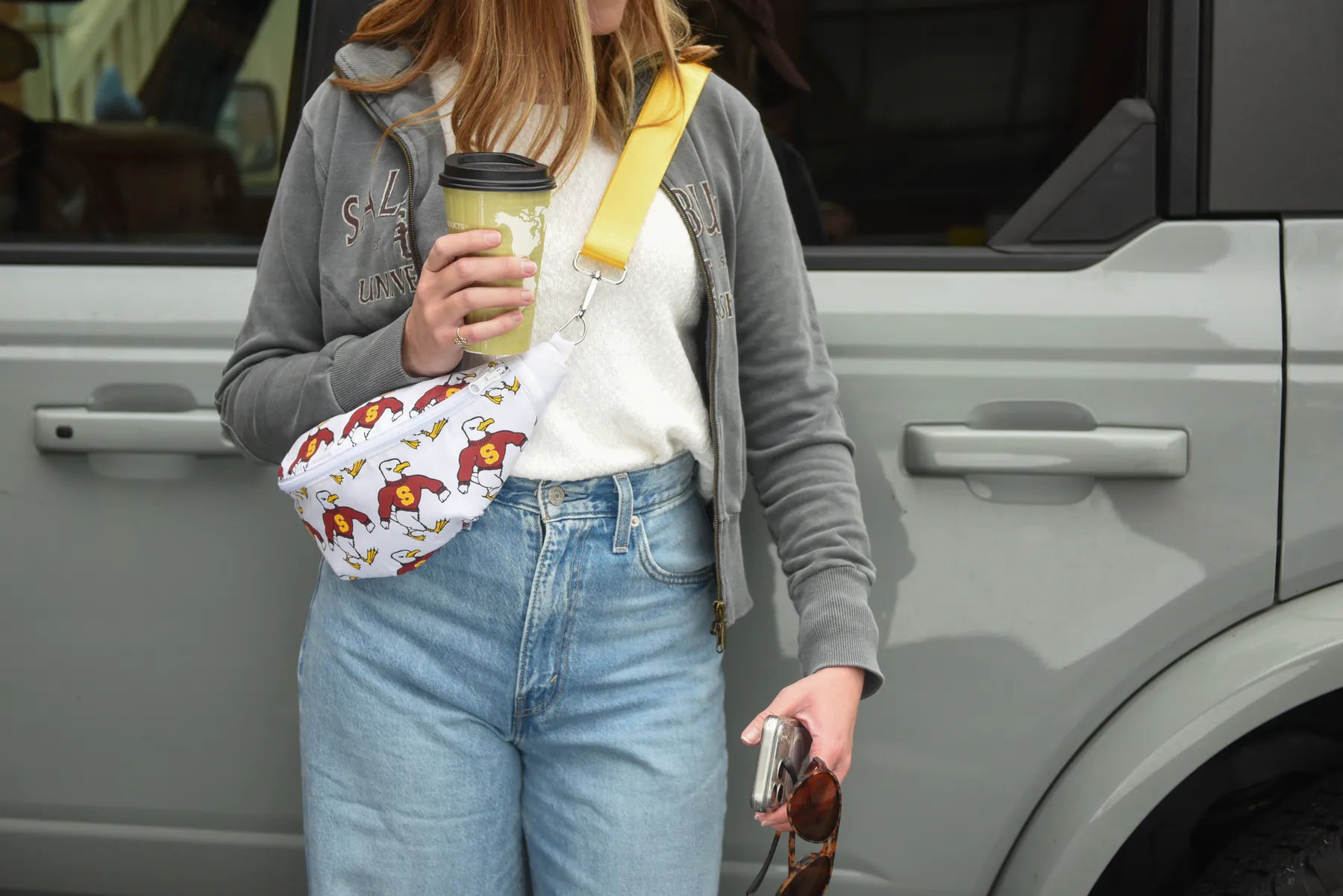 Full outfit view of a Salisbury-themed Sammy reversible sling bag worn crossbody with the white printed side