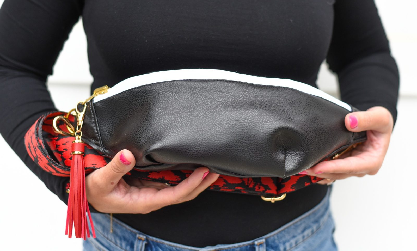 Close-up of the black leather-look side of a handmade reversible bag with a red strap