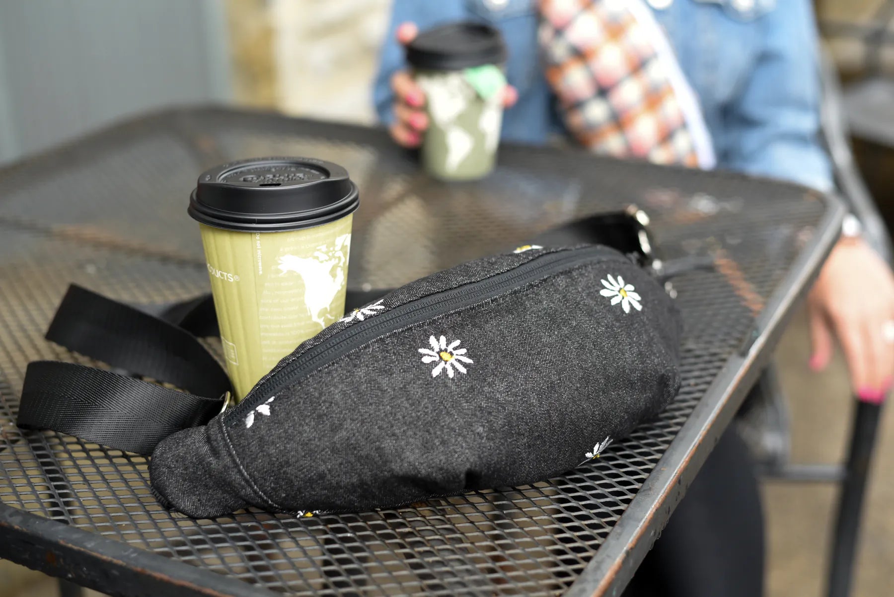 Black daisy print handmade reversible Switch Purse sling bag on a table for the contact page
